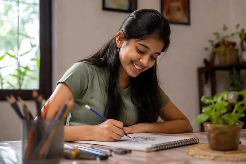 Indian student smiling while engaged in a creative hobby unrelated to schoolwork