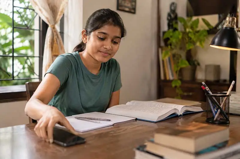 Indian student setting their phone aside while studying at a desk